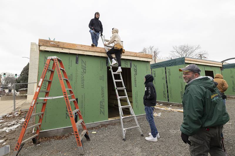 Whiteside Area Career Center building trades instructor Matthew Hicks (right) leads his class in the construction of the Sterling Main Street incubator pods.