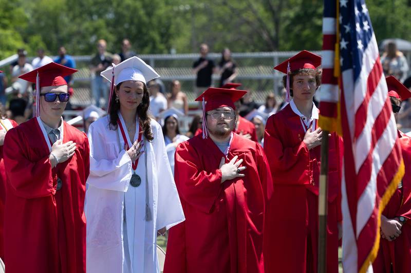 Graduates put hand over heart for the pledge allegiance on Sunday, May 18, 2025 at Hall High School in Spring Valley.
