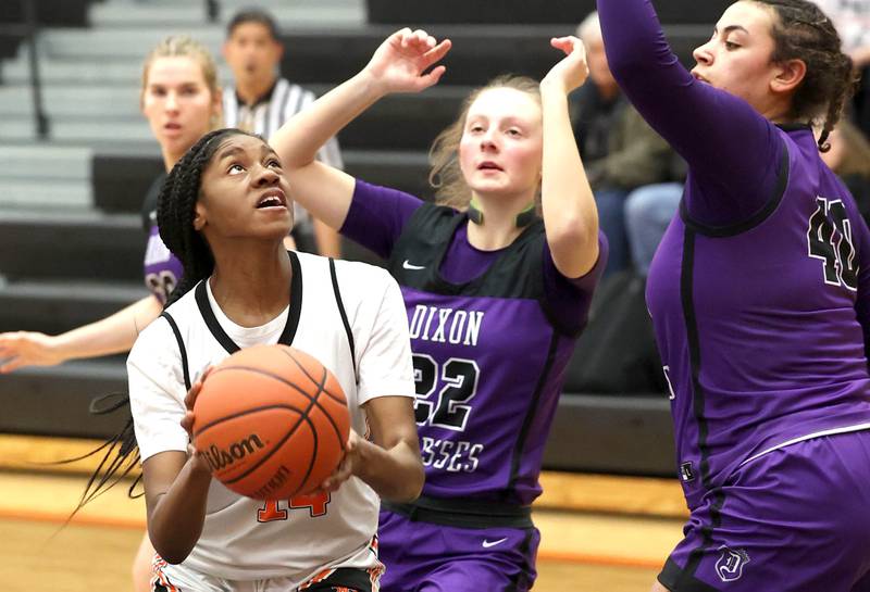 DeKalb’s Brytasia Long looks to score in the paint over Dixon’s Katie Drew and Hallie Williamson during their game Monday, Jan. 23, 2023, at DeKalb High School.