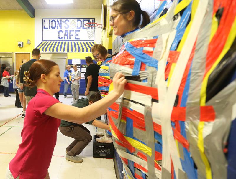 Student Gabby Hollars, places a strip of duct tape on social studies instructor Rebecca Shepherd during the "Tape The Teacher" fundraiser on Friday, March 20, 2026 at Logan Jr. High School in Princeton.