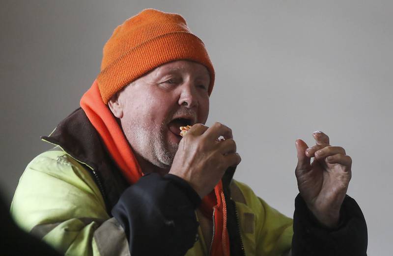Jimbo Phillip enjoys a slice of pizza during a free pre-Thanksgiving luncheon on Wednesday, Nov. 22, 2023, at the Woodstock train depot. This is the second year the meal that was provided through efforts of Warp Corps, MBI Cares, Isabel’s Family Restaurant, and Napoli’s Pizza, all located in Woodstock
