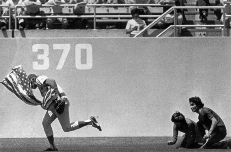** FILE ** Outfielder Rick Monday of the Chicago Cubs dashes between two men in the Dodger Stadium Outfield in Los Angeles, in this April 25, 1976 photo, snatching an American flag the men were about to burn. In honor of the 30th anniversary of his saving the American flag on April 25, 1976, the Los Angeles Dodgers will recognize Rick Monday on Sunday, April 23 with a video tribute. Monday, a Dodger broadcaster, will also be on hand to throw out the first ceremonial pitch. (AP Photo/Los Angeles Herald Examiner, James Roark)