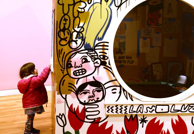 Zoey Novickas of Lombard turns the light on inside the one of art exhibits by Street Artist Sentrock (Joseph Perez of Chicago)  while also attending the Family Holiday Party at the Elmhurst Art Museum Saturday Dec 17, 2022.