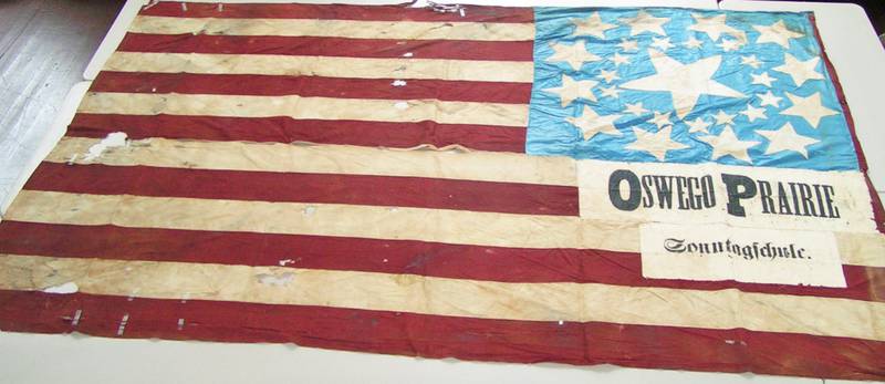 The star of “Grand Old Flags,” the current seasonal exhibit at Oswego’s Little White School Museum, is this “Great Star” pattern Civil War era banner flown by Oswego Prairie Evangelical Church Sunday School members who attended an 1873 farmers and laborers rally in Yorkville. It joins many other flags, from the national banner to flags commemorating such events as the nation’s Bicentennial in the exhibit, open through Sept. 29.