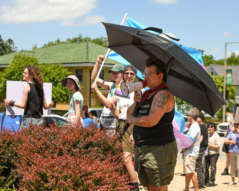 Killian Becker, 29, of DeKalb and one of the main organizers of the Trans Resilience Rally, welcomes everyone on Sunday, June 22, 2025, at Memorial Park in DeKalb. Organizers said the rally was to show public support for people they believe are unjustly and harmfully targeted under President Donald Trump's policies.
