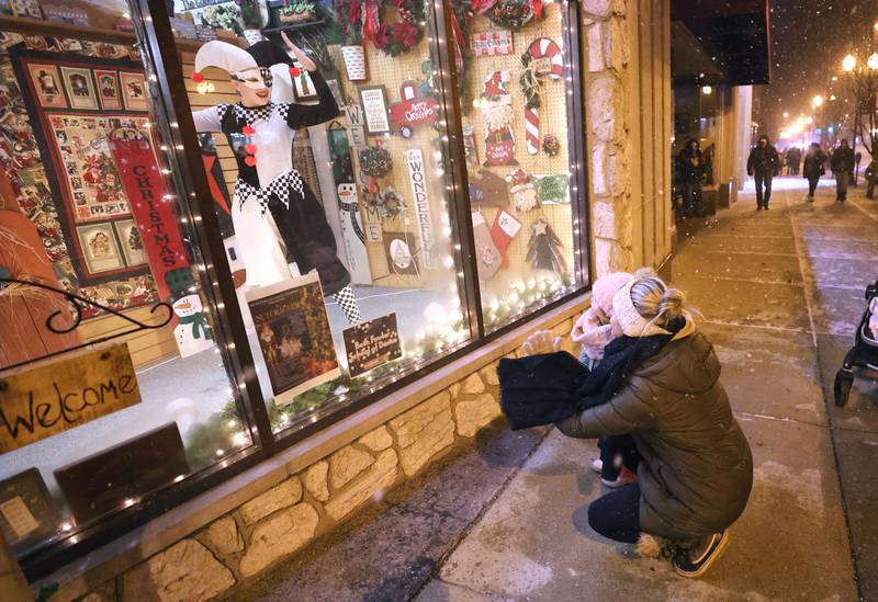 Reegan Debarba, 14, from DeKalb and a dancer with the Beth Fowler Dance Company, dances in the window of Made Just for You as Brecklynn Saffron, 2, and her mom Lori, from Sycamore, watch from the outside Friday, Nov. 18, 2022, during the Sycamore Chamber of Commerce's annual Moonlight Magic event in downtown Sycamore.