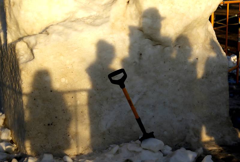 Snow carver Jesse Melloor’s shadow is cast on a block of snow as he talks to a group of Girl Scouts on Thursday, Jan. 30, 2025, while taking a break from carving their snow sculpture for America’s Snow Sculpting Invitational during Winterfest in Lake Geneva. Winterfest, runs through Feb, 2, 2025. The warm and rainy weather has slowed down the carving of the snow.