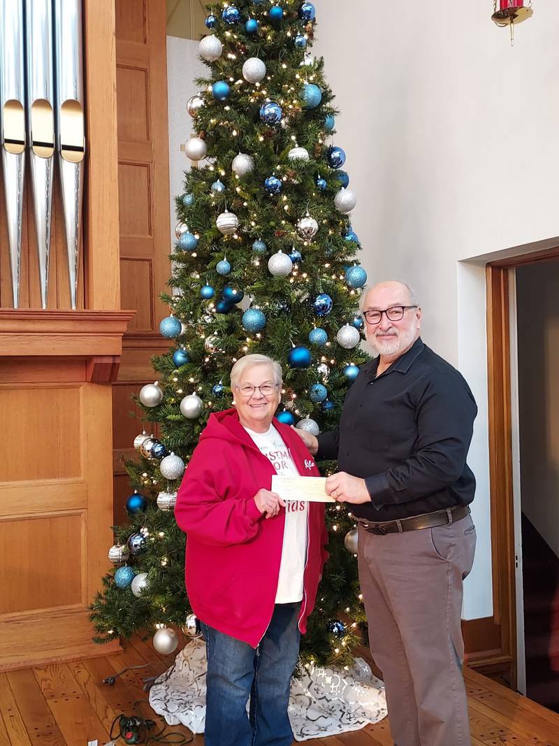 Pastor Michael Hickok presents a $7,000 check to Gale Hart of Christmas For Kids on Dec. 9.