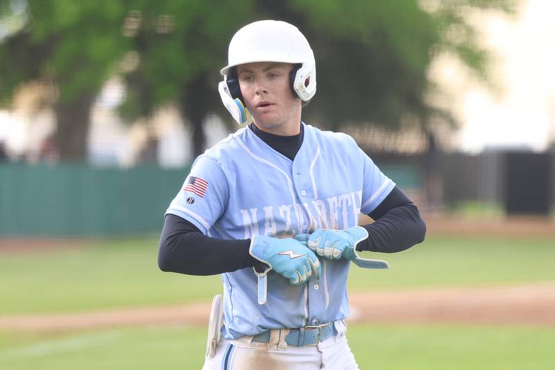 Nazareth’s Landon Thome takes off his gloves as he heads to first after drawing a walk against Joliet Catholic on Wednesday, April 29, 2026 in Joliet.