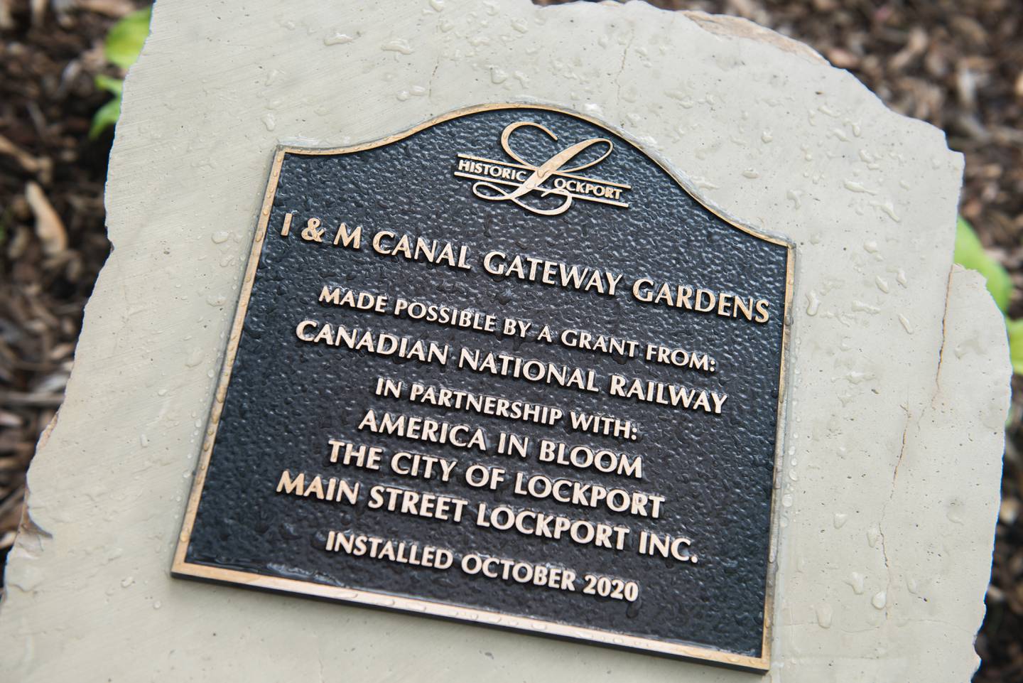 The plaque that identifies the new Illinois and Michigan Canal Gateway Gardens is mounted on limestone from Lockport's seven arch bridge.