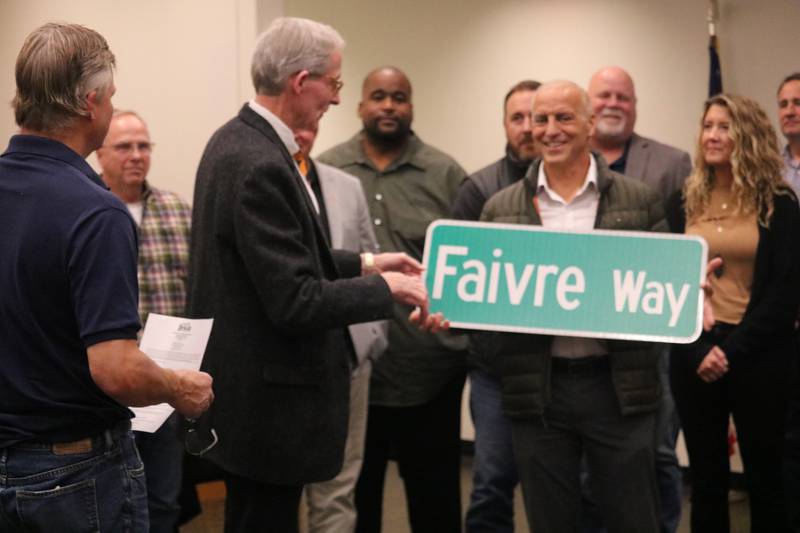 Bryan Faivre is seen Oct. 14, 2024, holding an honorary street sign, which dons his name, during a DeKalb City Council meeting.
