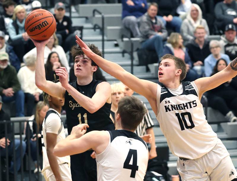Sycamore's Jake Shipley gets to the basket between Kaneland's Preston Popovich (left) and Troyer Carlson during their game Friday, Jan. 5, 2024, at Kaneland High School in Maple Park.