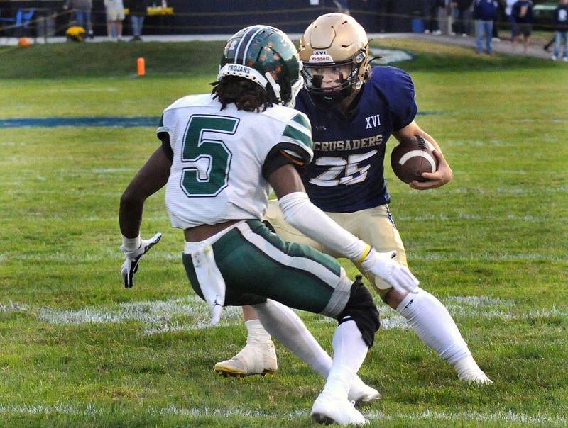 Jaxsen Higgins looks to avoid a tackle by Madison’s Marquez Smith in the 1st quarter Friday during the Marquette Crusader’s home opener.