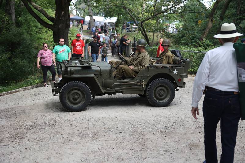 People wait as a WWII jeep with soldiers cross a road after a WWII battle re-enactment at Lockport Military History Days at Dellwood Park on Saturday, Sept. 9, 2023 in Lockport.