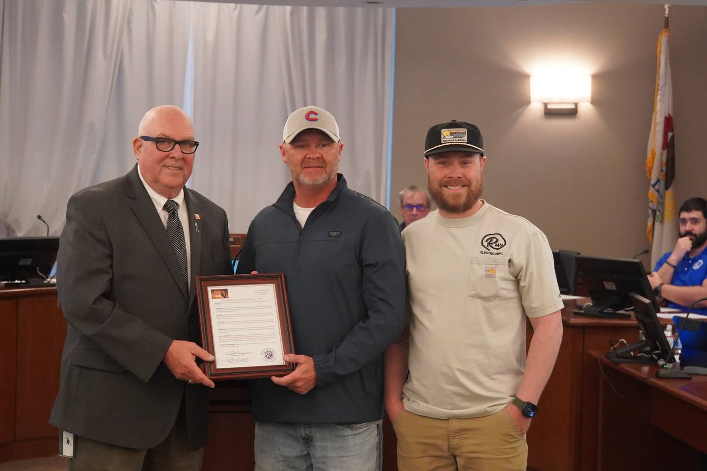 Rochelle Mayor John Bearrows (left) presents a proclamation to Rochelle Municipal Utilities Linemen Jason Burdin and Sean Kessler at the Monday, April 13 meeting of the Rochelle city council.