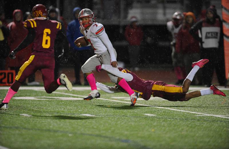 Palatine’s Dominick Ball tries to escape the grasp of Schaumburg’s Takumi Fred in a football game in Schaumburg on Friday, October 14, 2022.