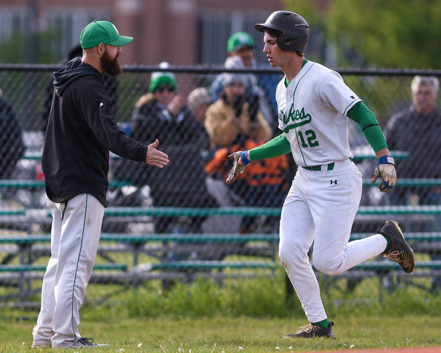 York's Josh Fleming (12) gets congratulated by his coach after hitting a two-run homer during the game on Monday May 19, 2025, while taking on Downers Grove North held at York High School in Elmhurst.