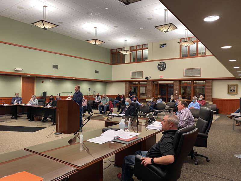 Trustees JR Westberg (front right) and Tim Hoeft (back right) listen as local resident Mike Figolah (at podium) delivers his public comment during a Huntley Village Board meeting on March 11, 2021.