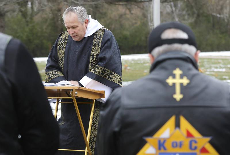Deacon Ken Giacone, from St. Elizabeth Ann Seton Catholic Church in Crystal Lake, prays during the Veterans Day flag placement ceremony Tuesday, Nov. 11, 2025, at the gravesites of veterans at McHenry County Memorial Park Cemetery in Woodstock. Members of the Knights of Columbus Patriotic 4th Degree from the Bishop Boylan Assembly placed American Flags at nearly 140 veterans' grave markers.
