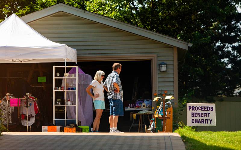 Mike Glaban looks over some of the items Connie Phistry, left, placed for sale at her home during Westmont’s weekend garage sales, Sunday, August 4, 2024.