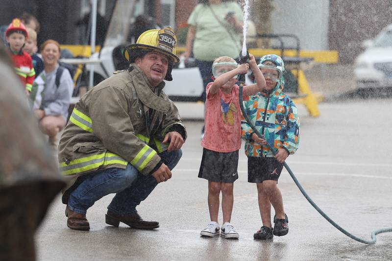Trevor Delehanty, left, helps Emmett Fullmer, 4, and Miles Kuhn, 4, during the Kiddie Water Fight at the 75th Annual Grundy County Corn Festival on Saturday, Sept. 28, 2024 in downtown Morris.