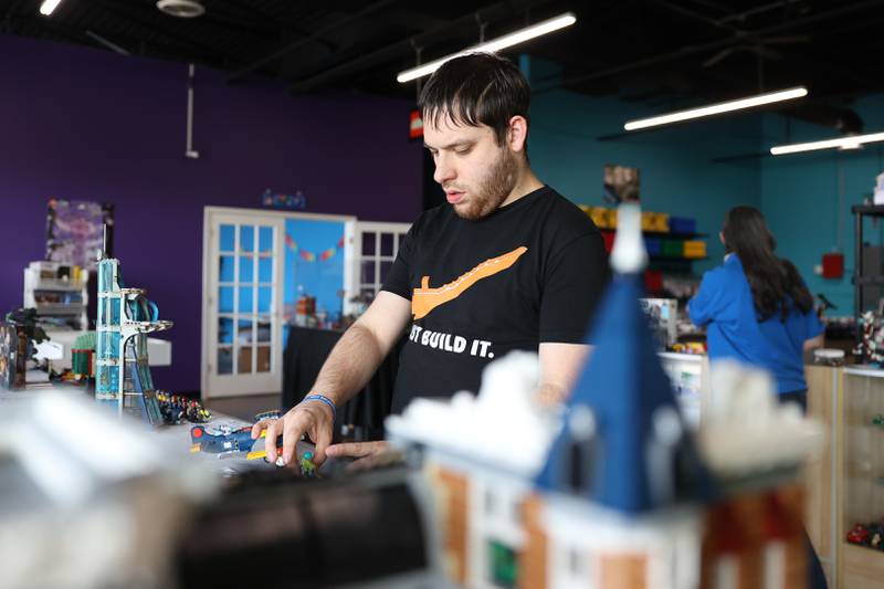 David Kravitz, an employee at Bricks & Minifigs LEGO store in Crest Hill, works on a display on Thursday, June 8, 2023.