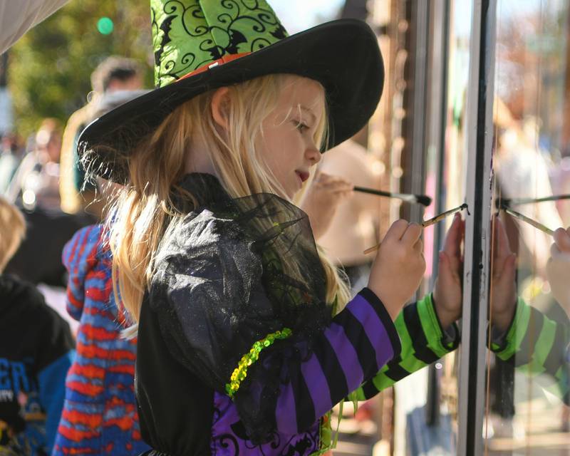 Downers Grove resident Penelope Hunt, 6, paints a window a Halloween window event held on Saturday Oct. 26, 2024, in downtown Downers Grove.