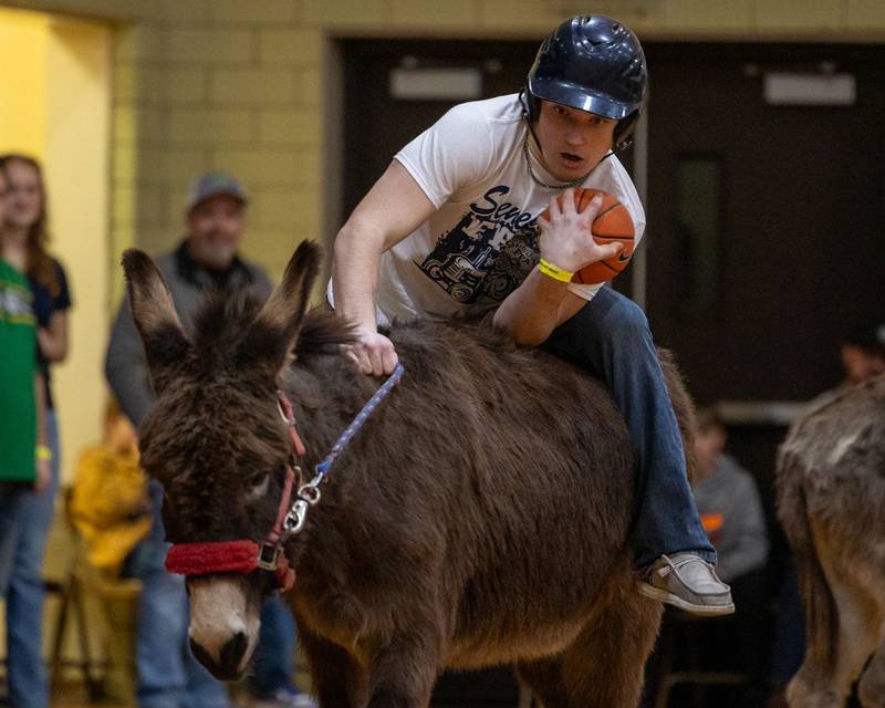 Joey Arnold struggles to stay mounted on donkey whilst holding ball in game of Donkey Basketball on Saturday, Feb. 7, 2026 at Seneca High School West Campus in Seneca.