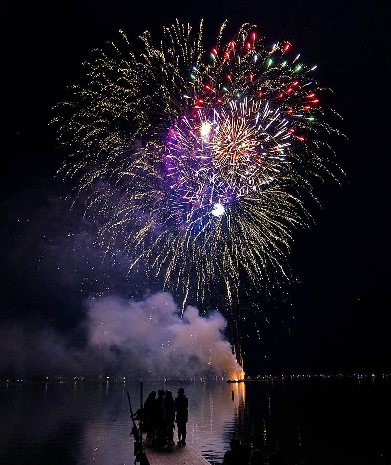 Young adults watch the fireworks show from a pier Sunday, July 2, 2023, at Crystal Lake’s Main Beach during Crystal Lake Annual Independence Day Celebration.