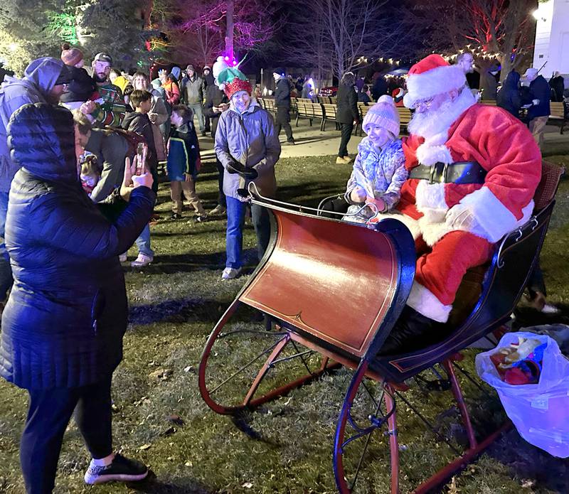 Claire Priller, 6, of Mt. Morris, sits with Santa in his sleigh for a photo during Mt. Morris' Christmas in the Village on Saturday, Dec. 7, 2024.