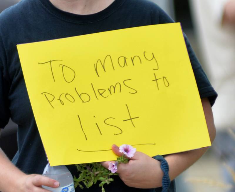 A woman carries a sign during Indivisible of Ogle County's rally on Saturday, Aug. 16, 2025 in Oregon to protest the policies and executive orders by President Donald Trump and his administration.