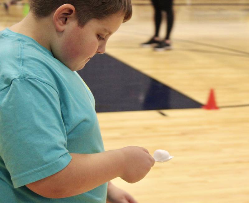 Caius Hoyle is a study in concentration as he moves with a cotton ball balanced on a spoon in a cooperative relay game on Tuesday during the Winter Mini Spark day camp at The Facility in Dixon.