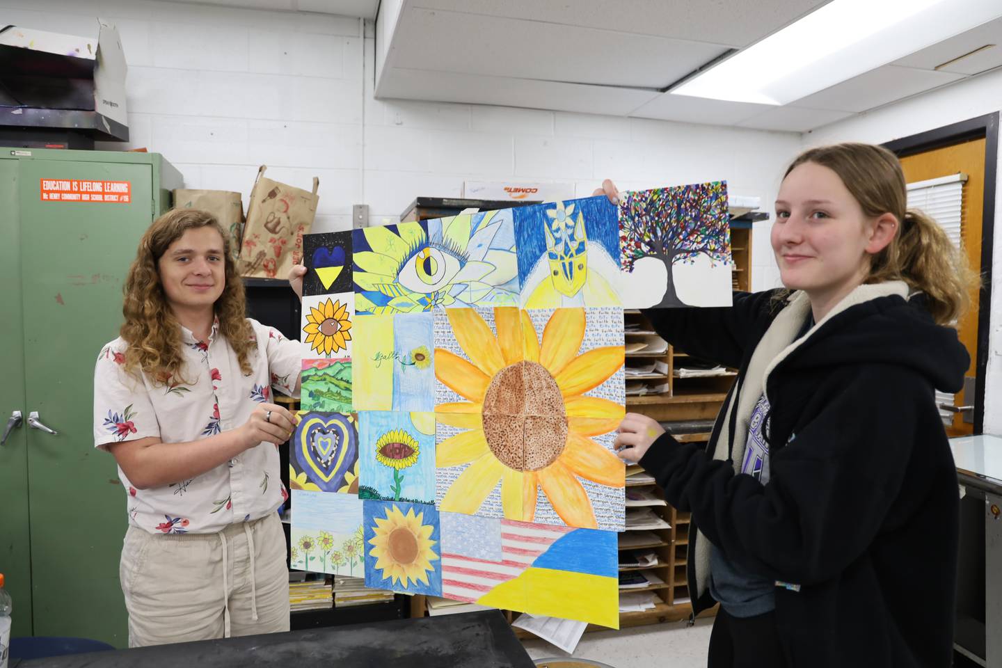 McHenry County High School students Gavin Wuchter, left, and Faith Riley, right, hold a quilt of artwork made by freshmen Art and Design 1 students to share with Ukrainian refugees. Photos of the art will be shared through Online Art Teachers K-12.