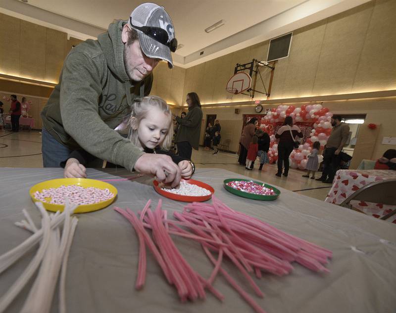 Aubrey Jo Zellers gets help from her father Bob in making a Valentine bracelet during a Valentine's Family Fun Day event Friday, Feb. 14, 2025, at Lincoln Elementary School in Ottawa.