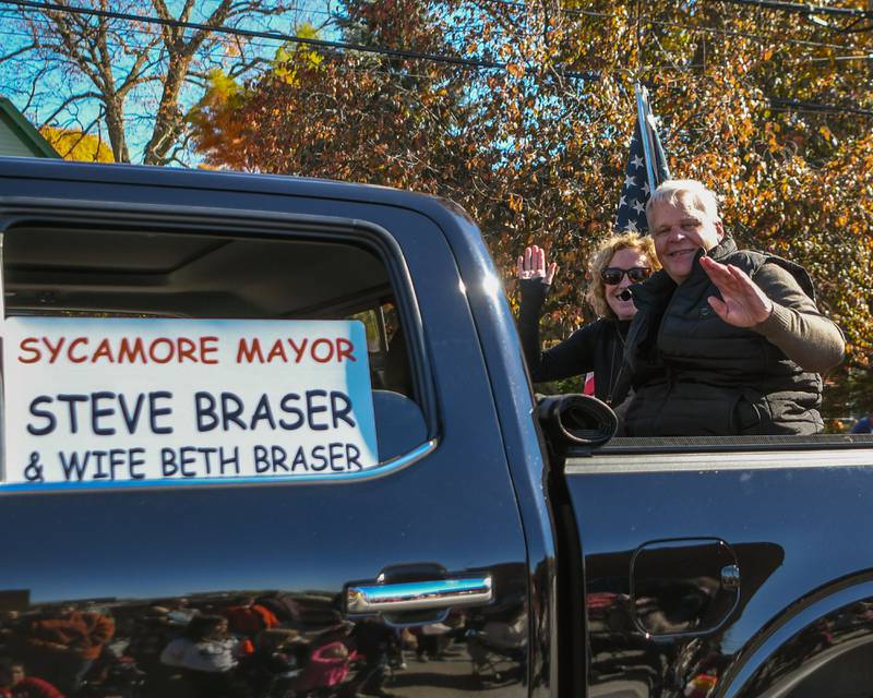 Sycamore Mayor Steve Braser and wife Beth Braser wave from their float in the Pumpkin Parade on Sunday Oct. 28, 2024, downtown at the 63rd annual Sycamore Pumpkin Festival.