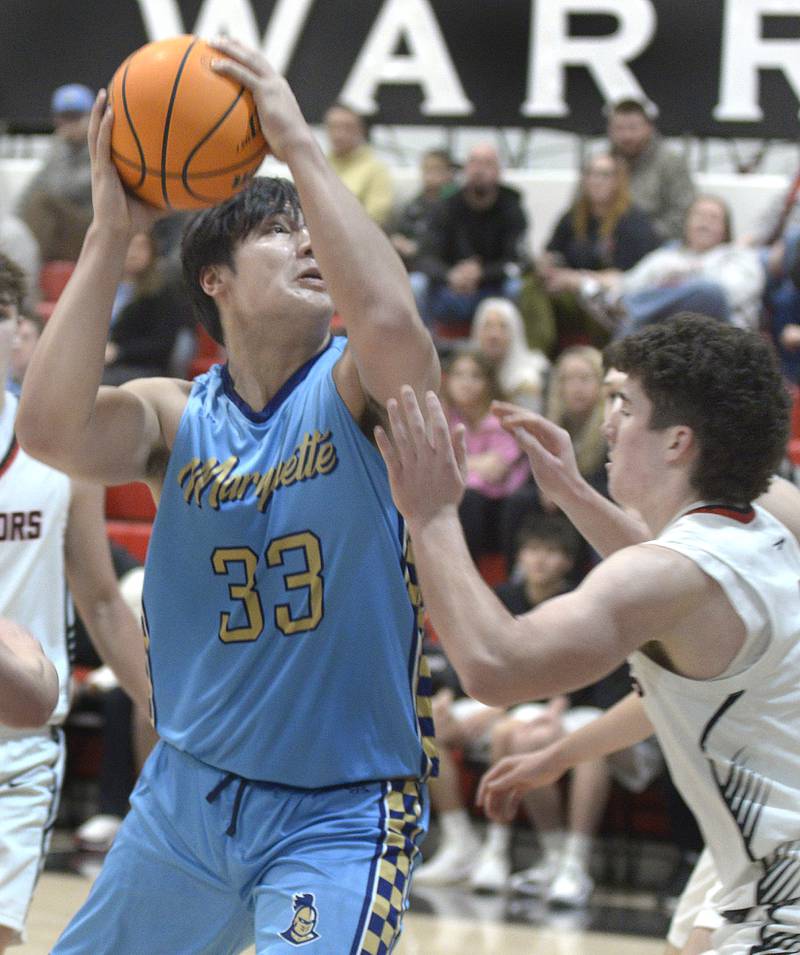 Marquette’s Michael Coutts eyes the basket as Woodland’s Brezdyn Simons sets to block in the 1st period Friday at Woodland.