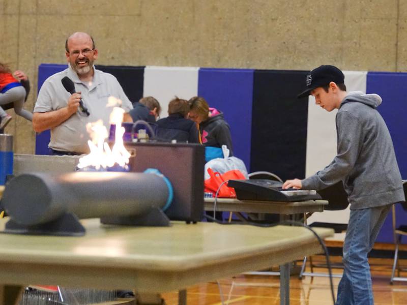 Dane Passwater (playing piano) and Matthew Johll (holding microphone) demonstrate how an amplifier connected to a piano can control the flames on Friday, April 19, 2024 at Illinois Valley Community College's SciFest in Oglesby.