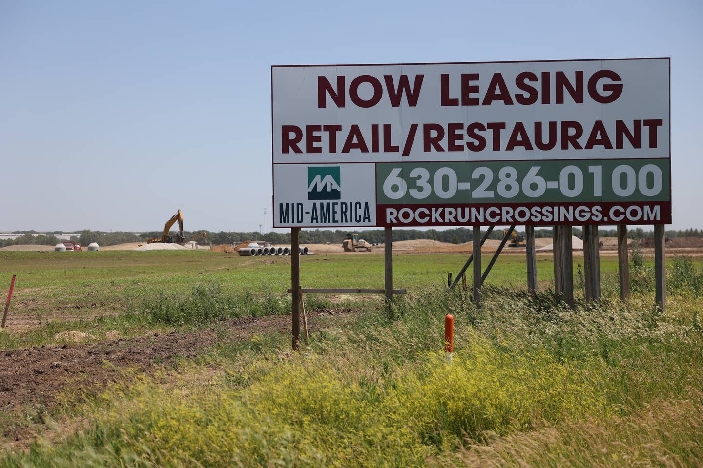 Land clearing work takes place in the background of a sign to attract businesses at the site of the 310 acre Rock Run Crossing mix-use project near the intersection of I-55 and I-80. Tuesday, June 21, 2022 in Joliet.