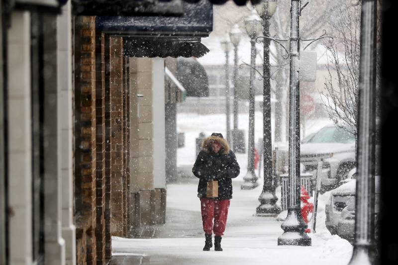 A pedestrian walks up North William Street as snow falls in downtown Crystal Lake on Thursday, Feb. 4, 2021.