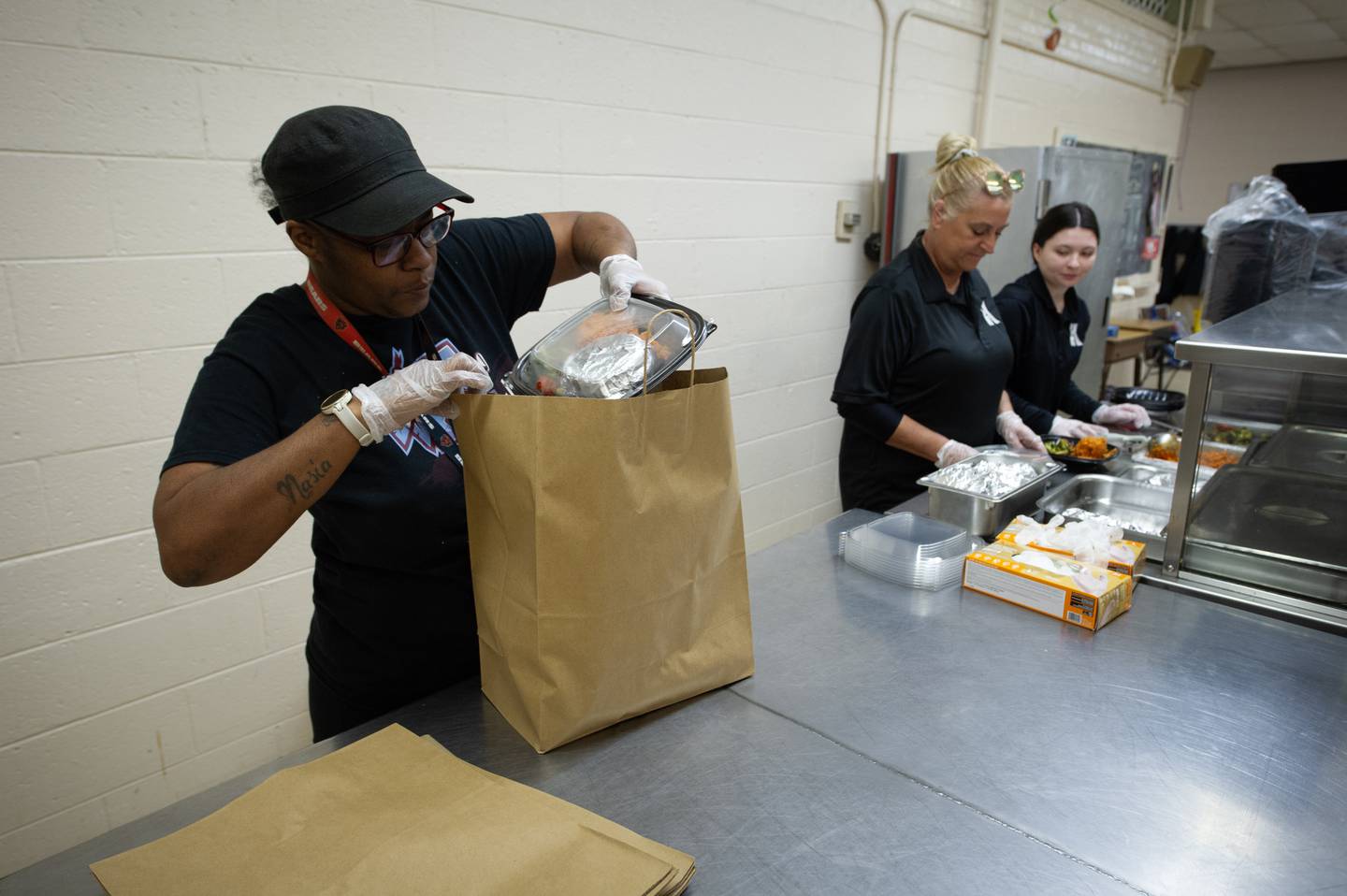 Sheila Martin, left, Kankakee Taft School employee, bags a take-out meal, as Traci Annis, center, and Kristen Bowen, right, Kankakee High School employees, prepare other meals at Lincoln Cultural Center in Kankakee on Thursday, March 12, 2026.