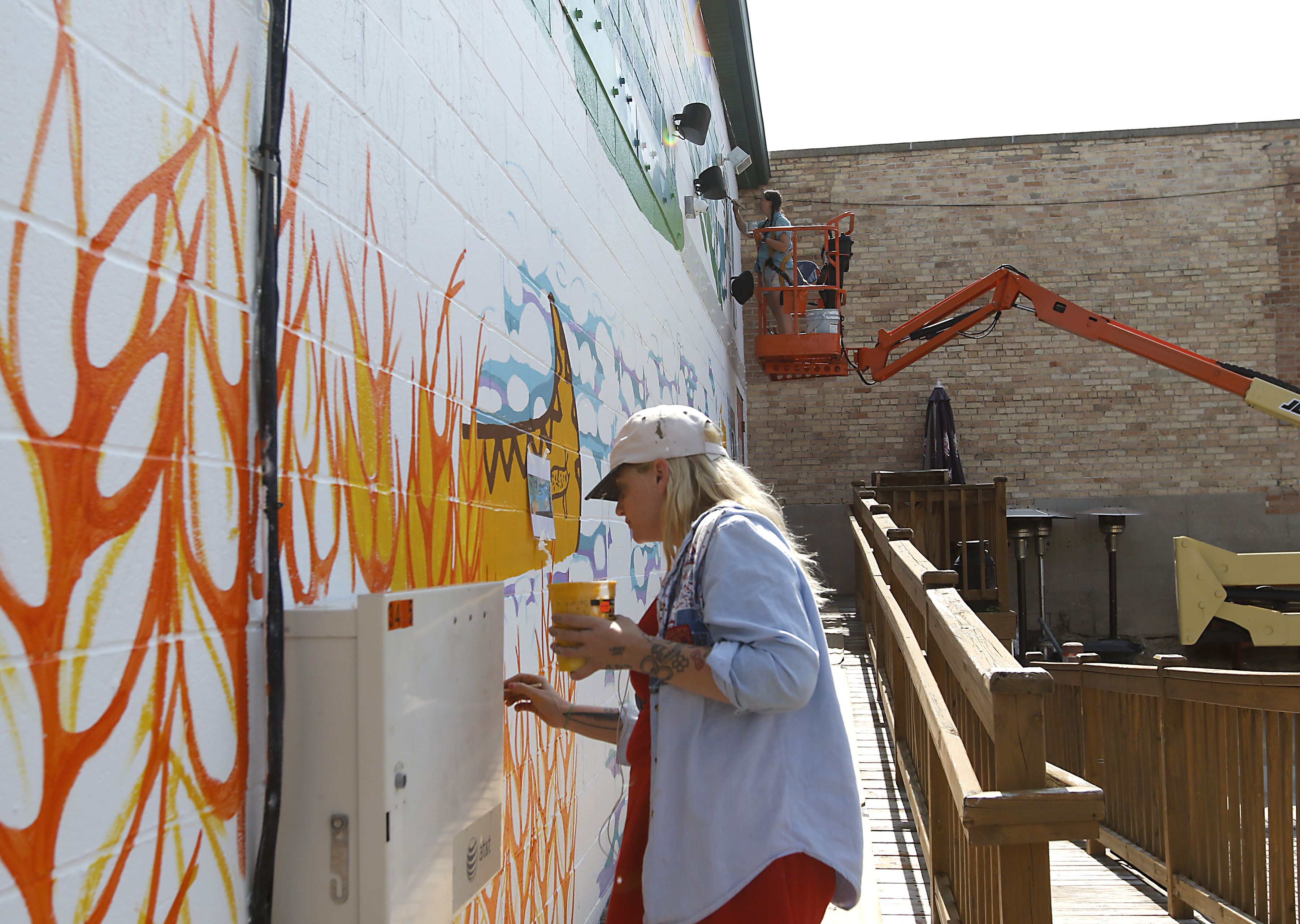 Melinda Cook (foreground) and Jenny Mathews (background) paint a mural on Thursday, June 19, 2025, on the side of the McHenry Brewing Co., in McHenry. This is one of two new McHenry murals in McHenry. 