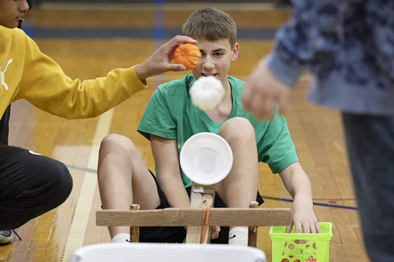 Eighth grader Rylan Steagall fires off pumpkins one after another with the help of teammates Thursday at Rock Falls Middle School. Teammates had to work together to design, build and decorate their device.