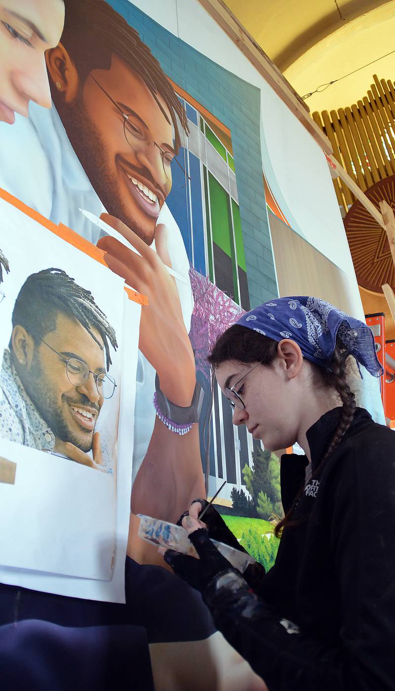 Morgan Phillips works on an arm of one of the contemporary figures in the mural. Phillips and Emily Maze, both Illinois Valley Community College alums, also have worked on other public art murals in the area.