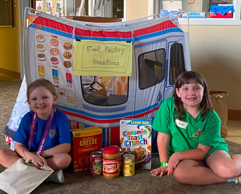 Elodie and Kaylee show off the food truck at Trinity Church United Methodist that was filled with 185 non-perishable food items for the Kendall County Community Food Pantry. The children collected these items as part of their outreach program during Vacation Bible School.