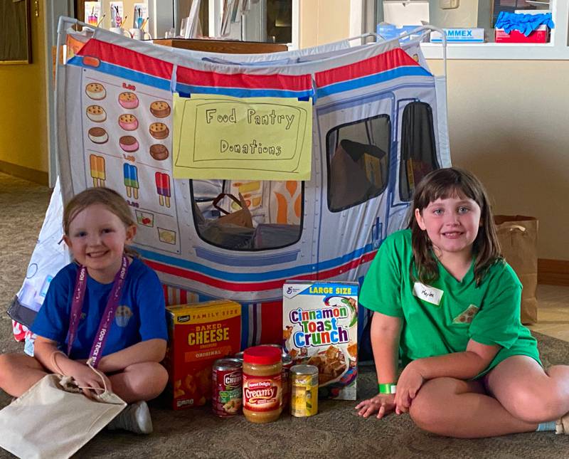 Elodie and Kaylee show off the food truck at Trinity Church United Methodist that was filled with 185 non-perishable food items for the Kendall County Community Food Pantry. The children collected these items as part of their outreach program during Vacation Bible School.