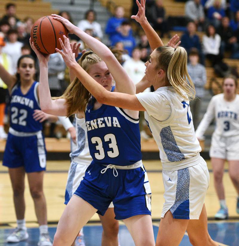 Geneva's Lauren Slagle (33) is pressured under the basket by St. Charles North's Reagan Sipla during Thursday’s girls basketball game in St. Charles.