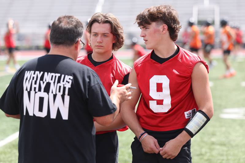 Lincoln-Way West quarterbacks Drew Litke, center, and Chase Hetfleisch listen to a coach during a 7-on-7 scrimmage at Lincoln-Way East on Tuesday, July 18th, 2023 in Frankfort.