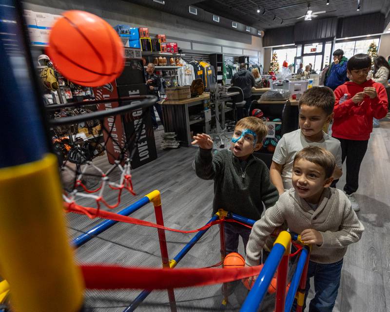 (from left) Jaxson Puga shoots basketball as Vinny Puga and Benny Puga watch on at the annual Christmas in the Valley on Saturday, November 15, 2025 at the Locker Room in Spring Valley.
