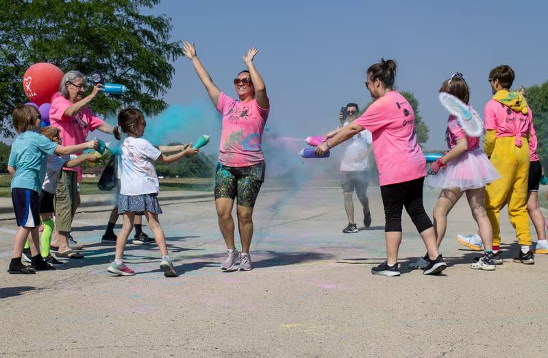 A runner raises their hands up in celebration after crossing the finish line during CASA DeKalb County's annual 5K Color Run Saturday, June 3, 2023. Approximately 140 people ran in the color run.
