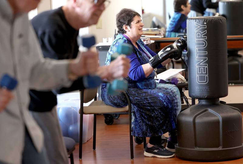 Jill Klecka hits the bag as others work out with weights Friday, April 28, 2023, during Rock Steady Boxing for Parkinson's Disease class at Northwestern Medicine Kishwaukee Health & Wellness Center in DeKalb. The class helps people with Parkinson’s Disease maintain their strength, agility and balance.